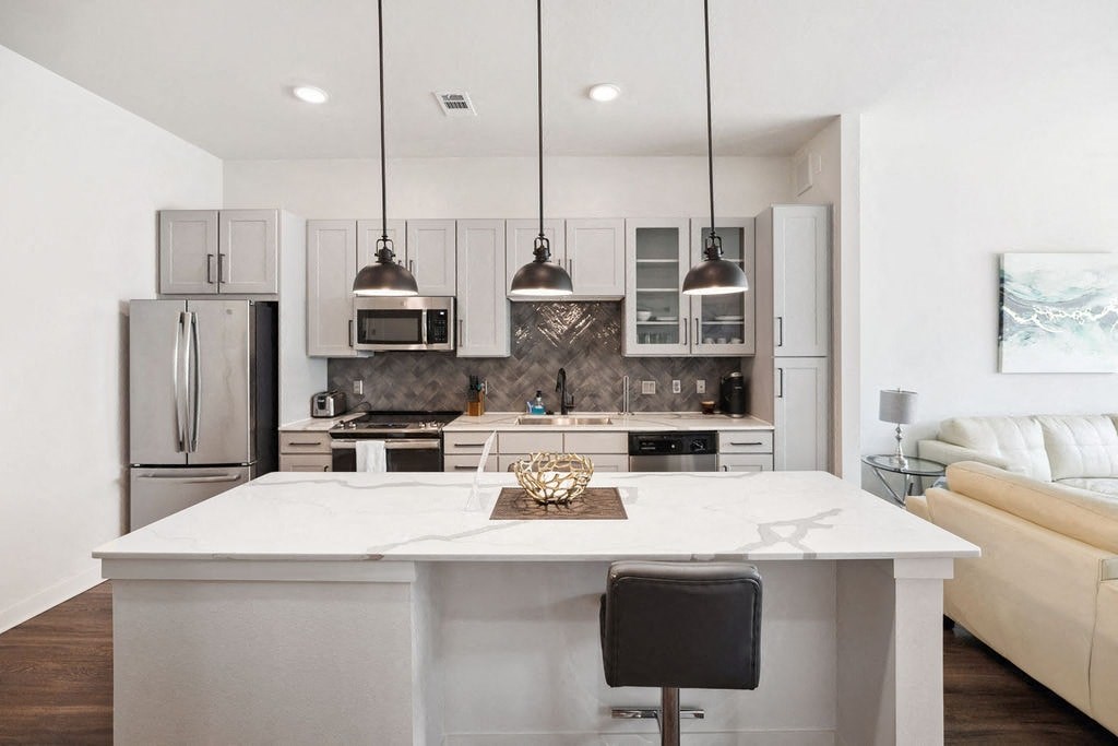 A modern kitchen with a white island and a black chair.