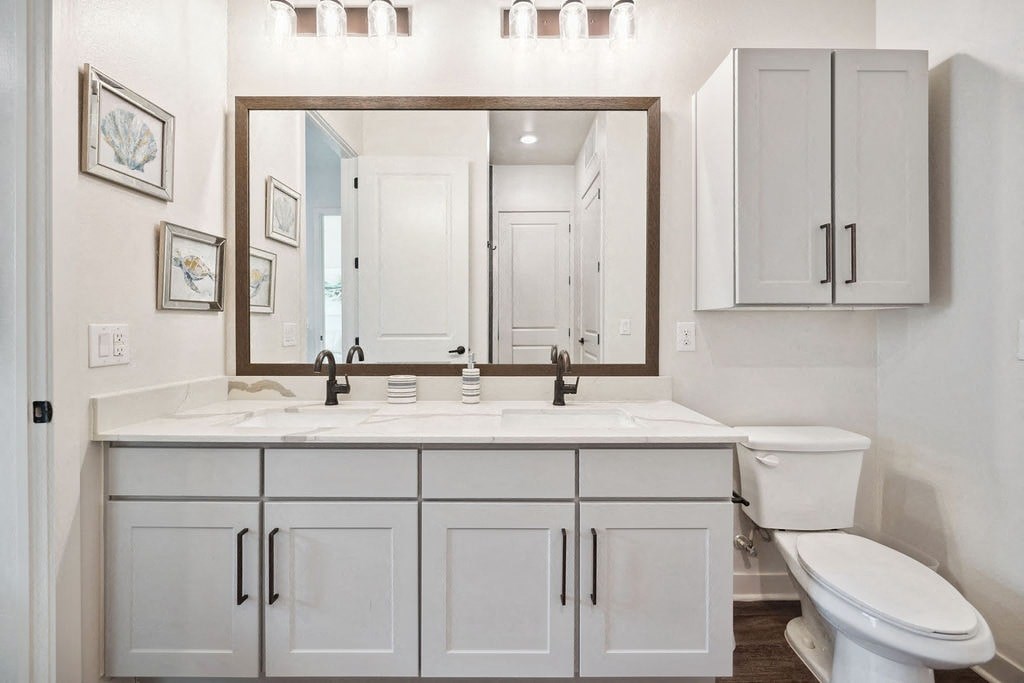 A bathroom with a white toilet, sink, and cabinets.