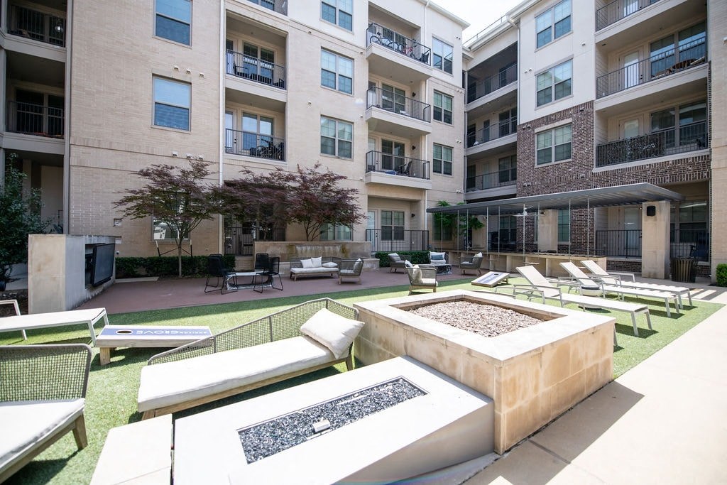 A sunny day at apartment complex with a pool and lounge chairs.
