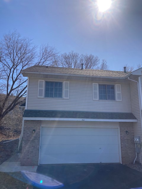 A house with a white garage door and a tree in front.