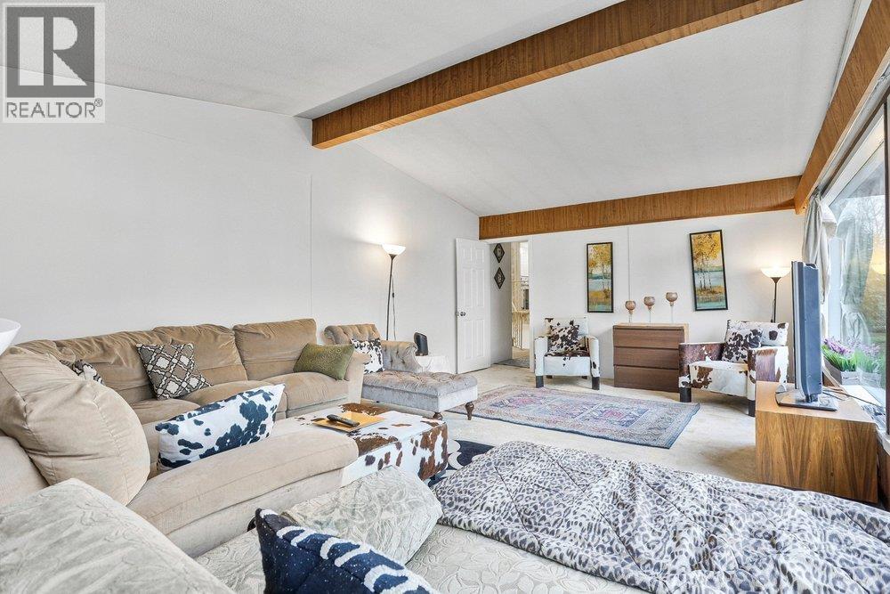 A living room with a red coffee table and a black couch with a red and black plaid blanket on it.