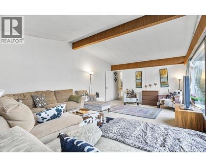 A living room with a red coffee table and a black couch with a red and black plaid blanket on it.