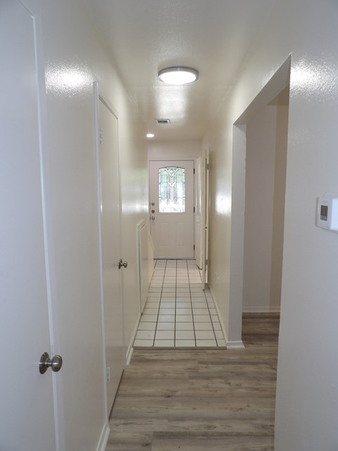 A long white hallway with a tiled floor and white walls.