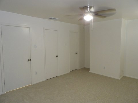 A room with a ceiling fan and three doors.