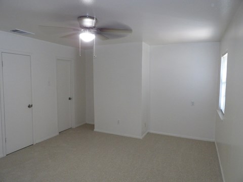 A room with a ceiling fan and carpeted floor.