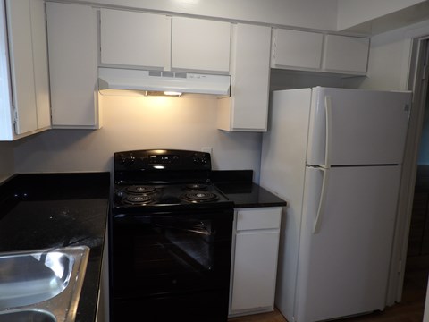 A black stove top oven sits next to a white refrigerator in a kitchen.