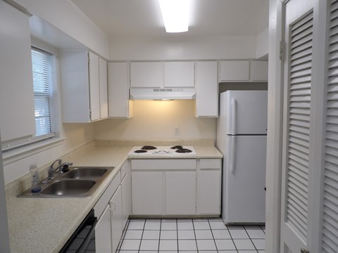 A kitchen with white cabinets and a white refrigerator.