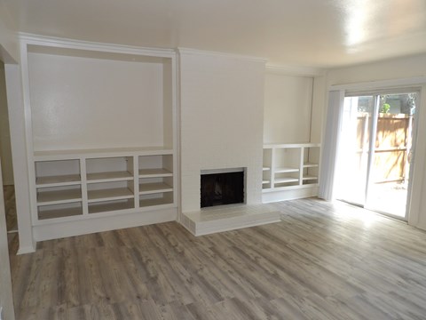 A white room with a fireplace and shelves.