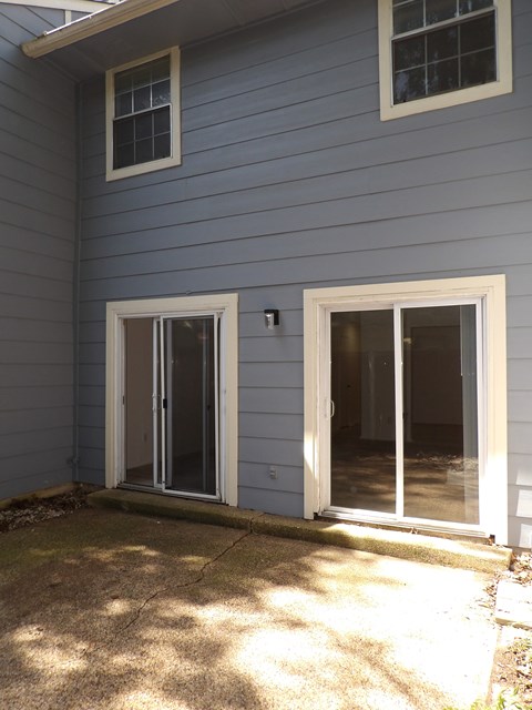 A house with a grey siding and two sliding glass doors.