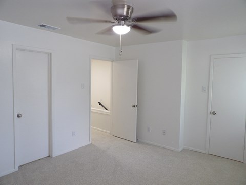 A room with a ceiling fan and carpeted floor.