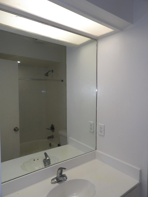 A white sink in a bathroom with a mirror above it.