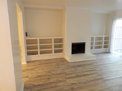 A living room with a fireplace and built-in shelves.