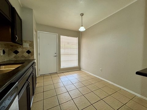 A kitchen with black cabinets and a tiled floor.