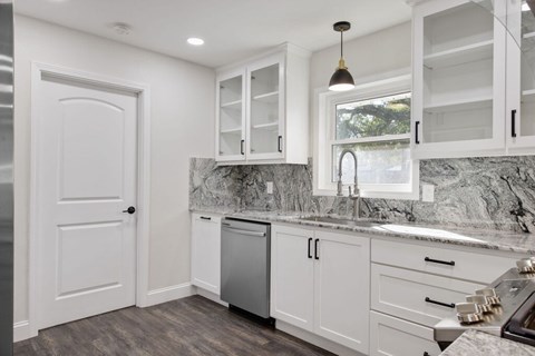 A kitchen with white cabinets and a marble countertop.
