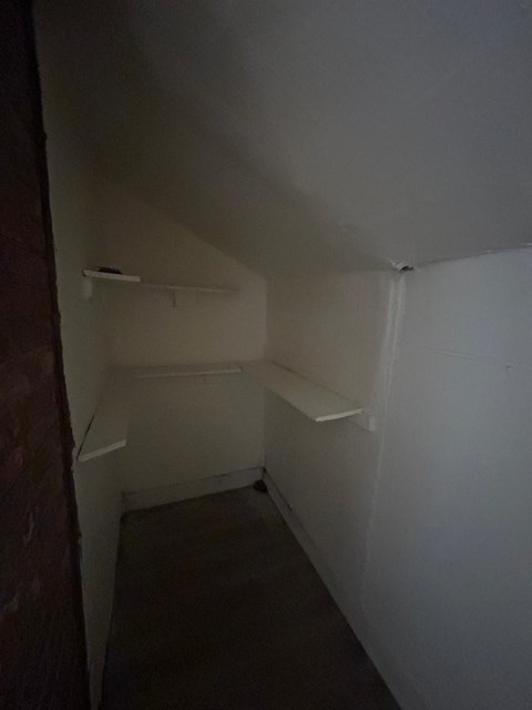 A white closet with a door and a shelf.