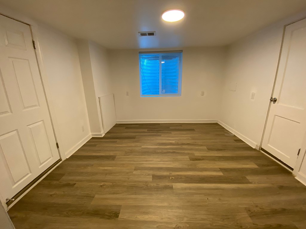 A room with wooden flooring and white walls.