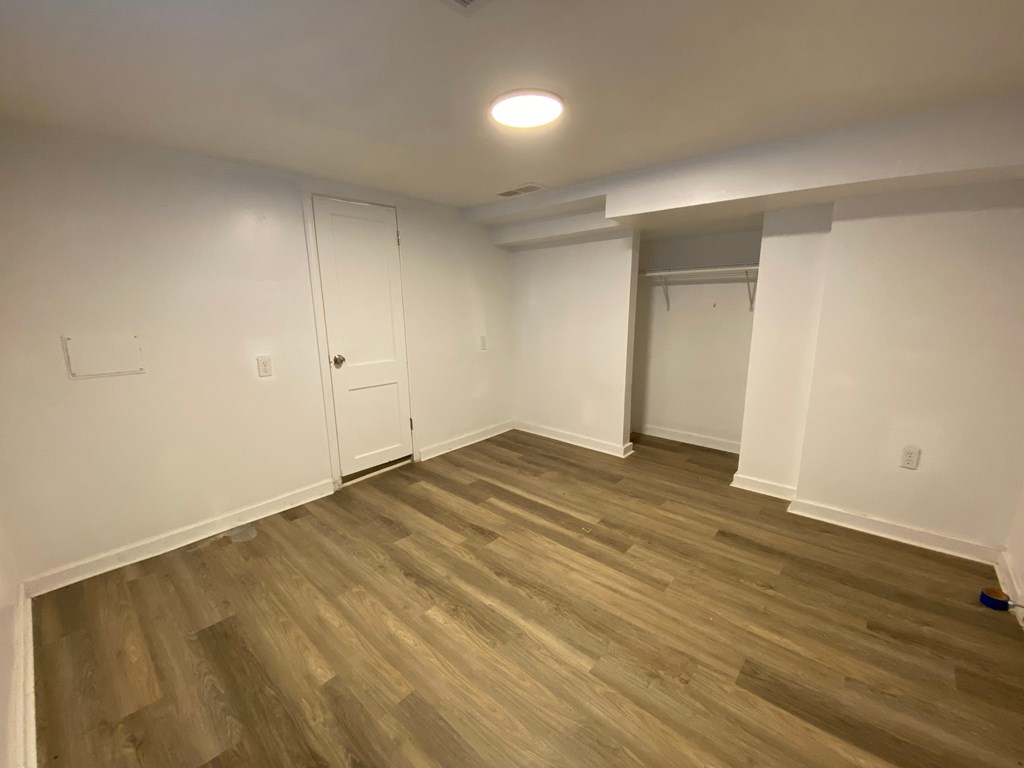 A room with wooden flooring and white walls.