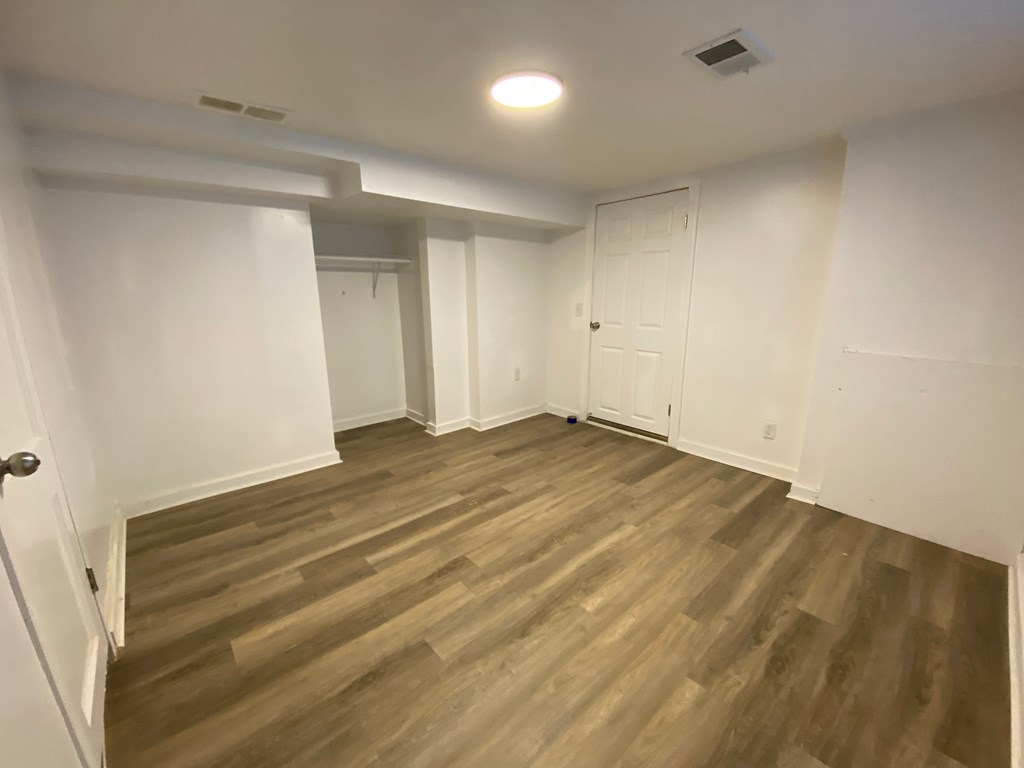 A room with wooden flooring and white walls.