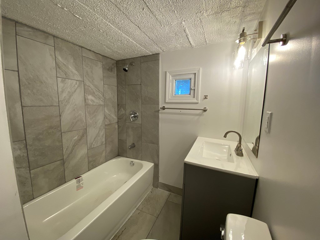 A bathroom with a white tub, sink, and toilet.