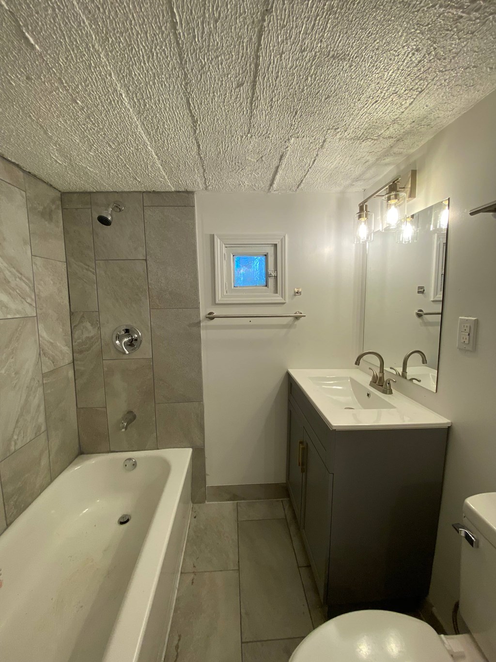 A bathroom with a white tub, sink, and toilet.