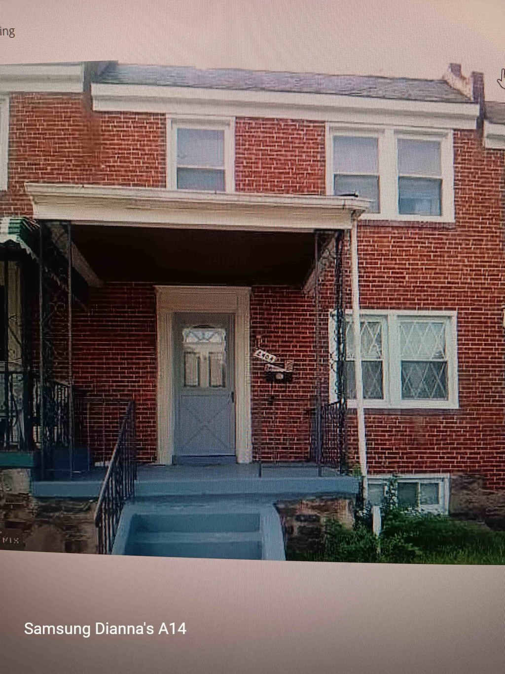 A red brick house with a white door and a small porch.