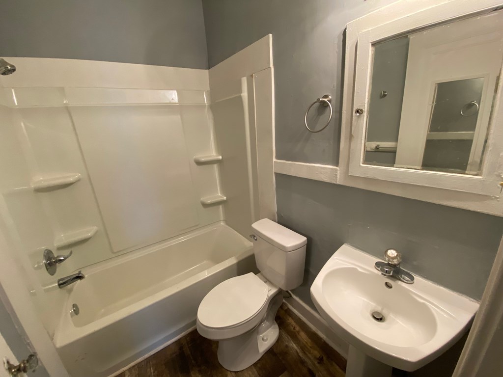 A white toilet sits next to a white sink in a bathroom.