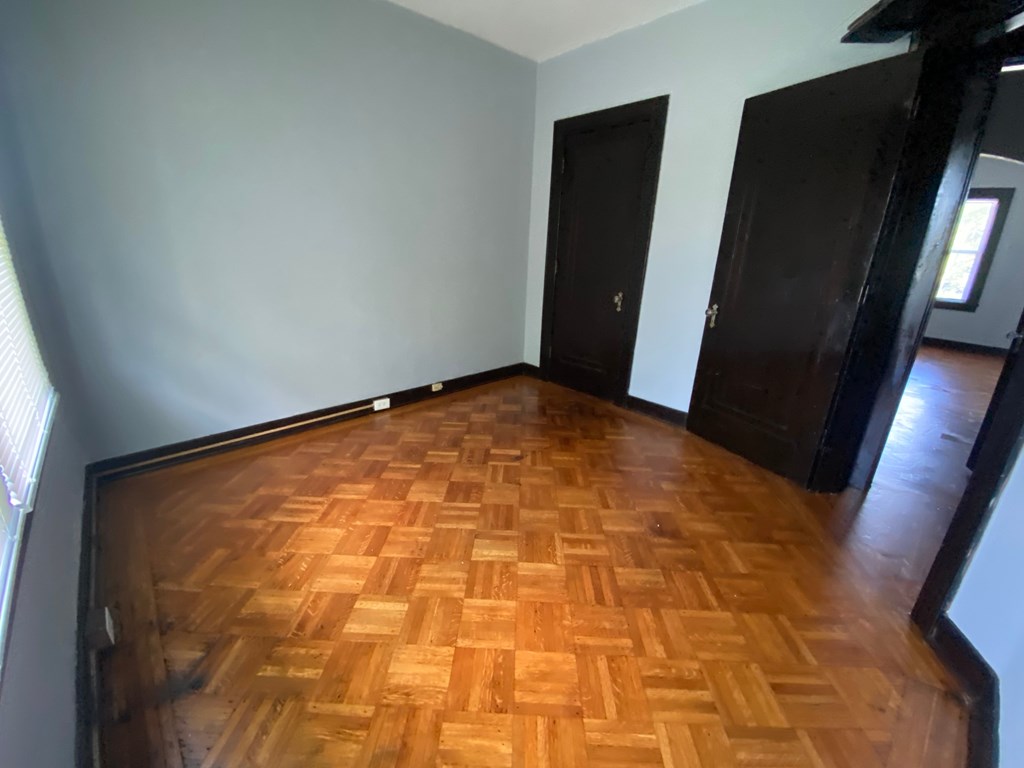 A room with a wooden floor and two dark wood doors.