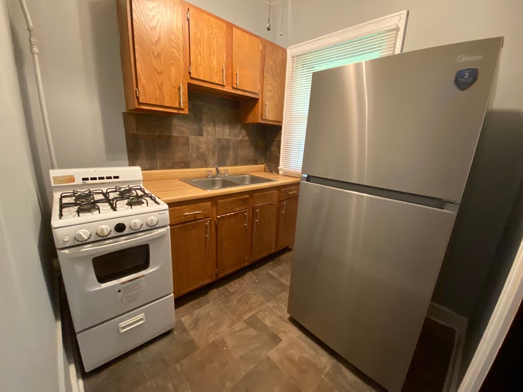 A kitchen with a stove, sink, and refrigerator.
