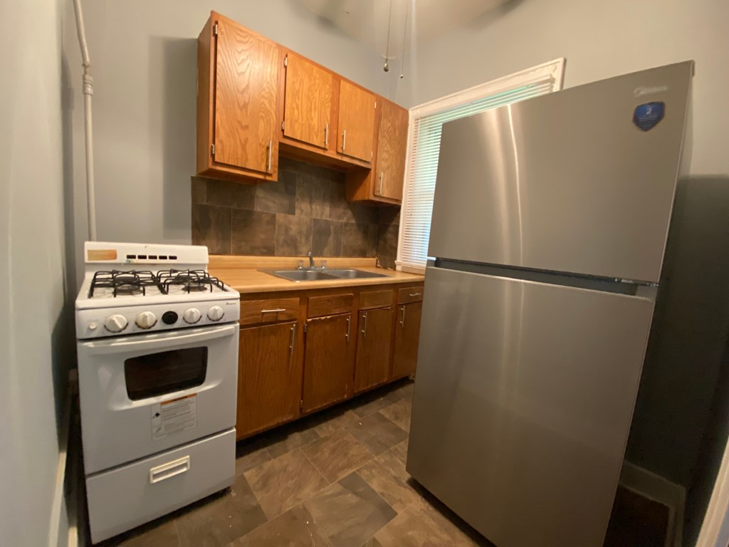 A kitchen with a stove, sink, and refrigerator.