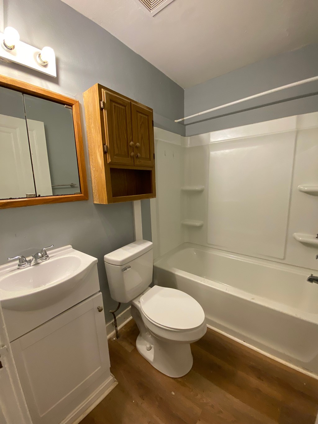 A white toilet sits in a bathroom next to a sink and a bathtub.