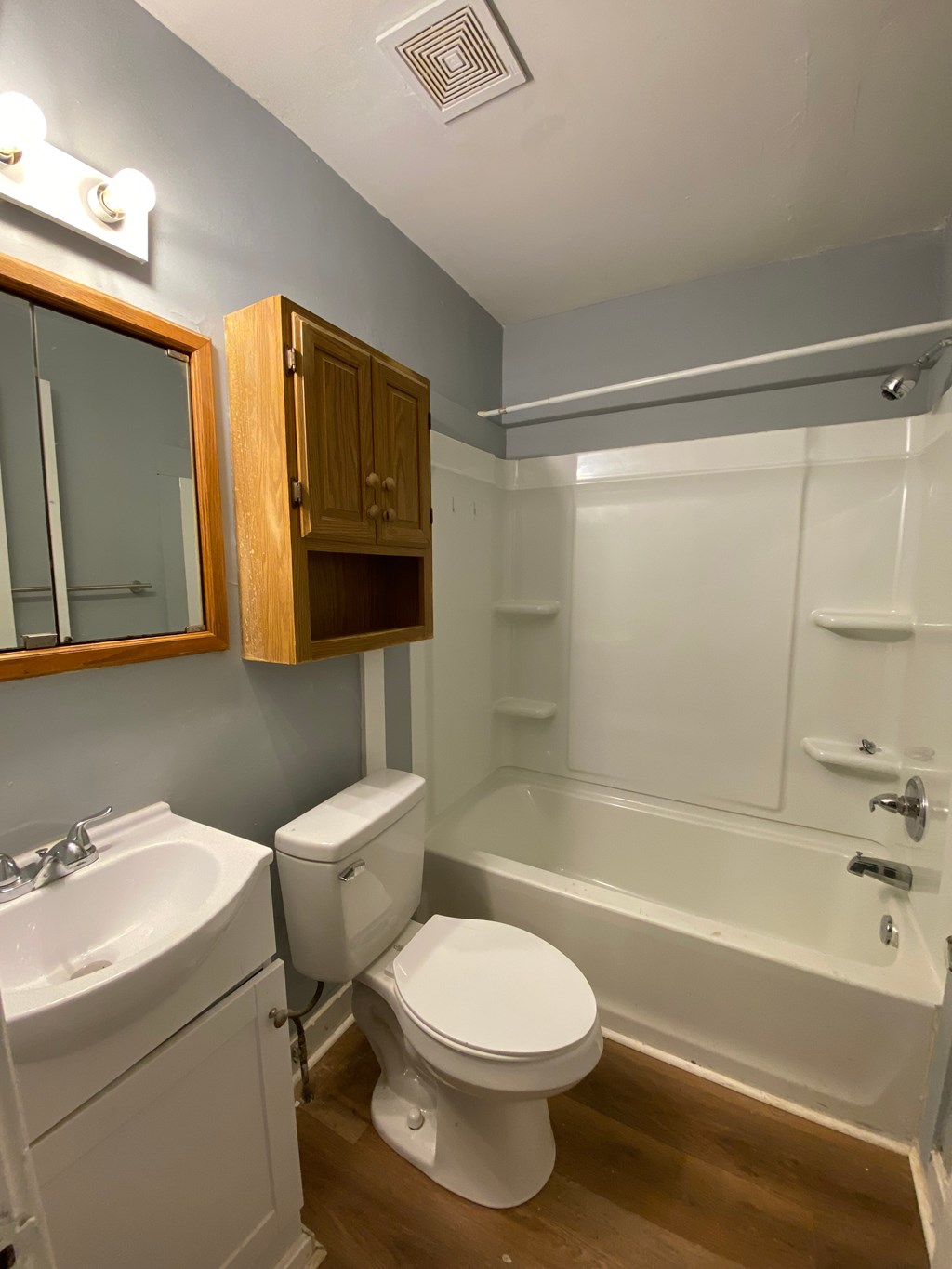 A white toilet sits under a mirror in a bathroom.