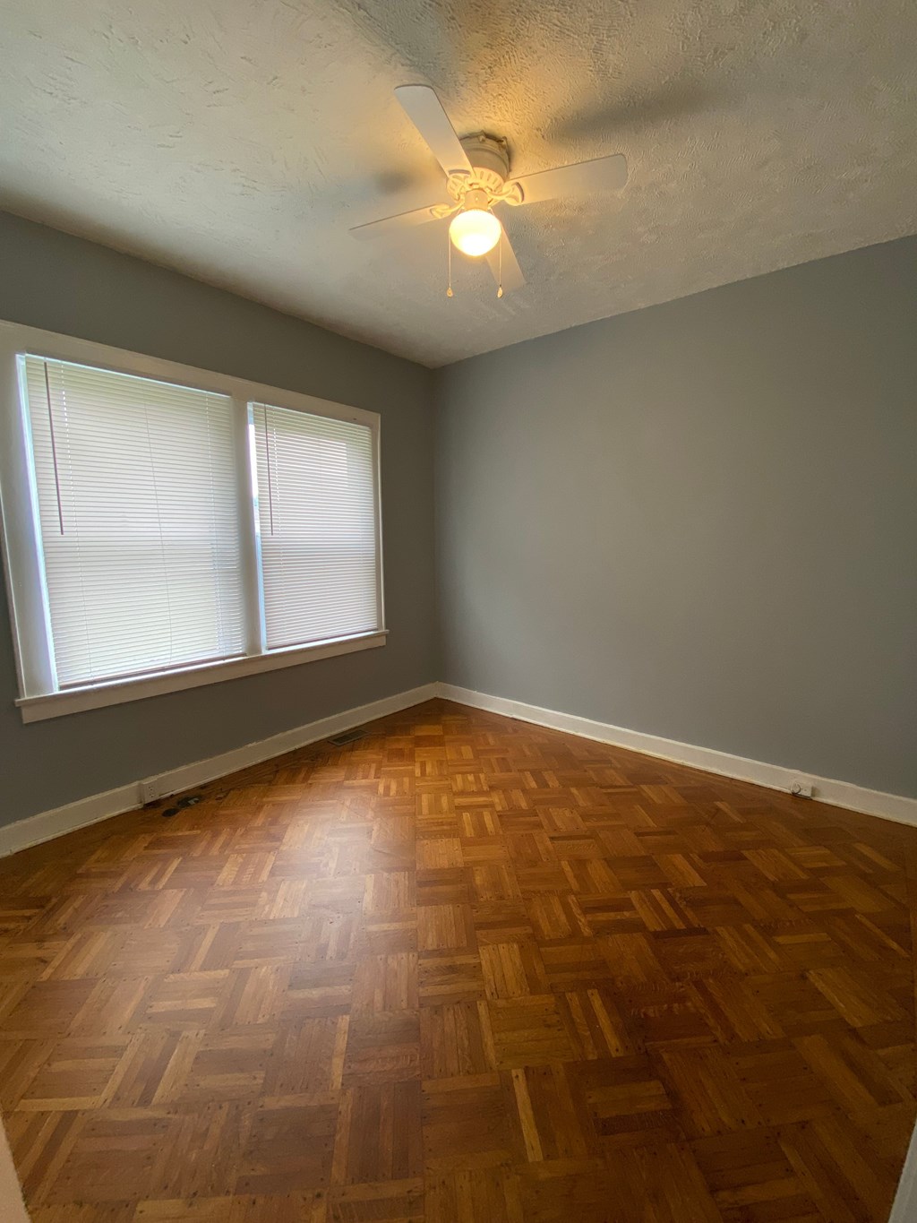 A room with a wooden floor and a ceiling fan.