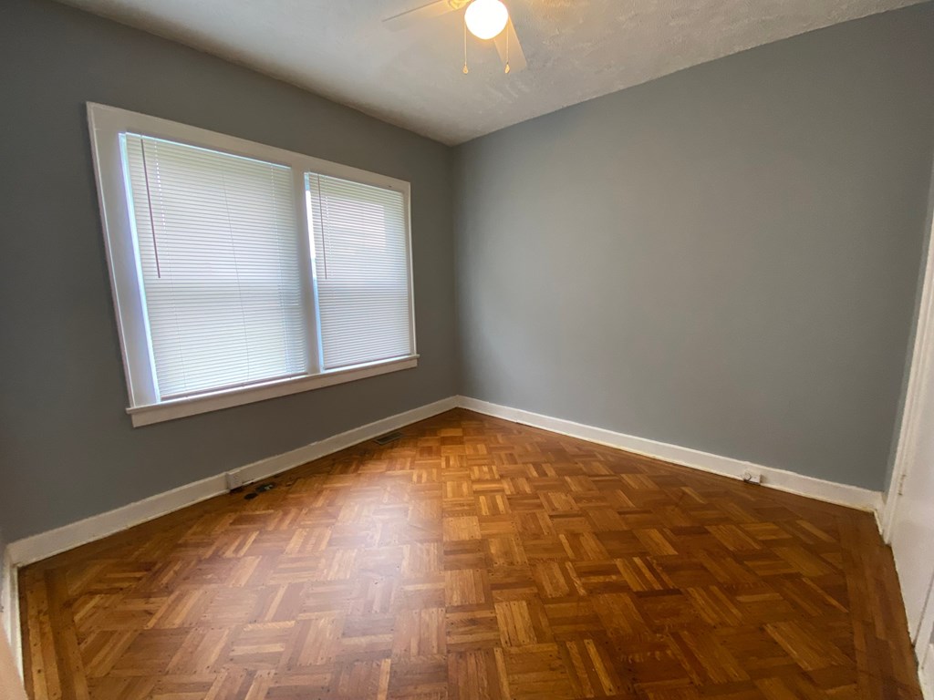 A room with wooden flooring and a window with blinds.