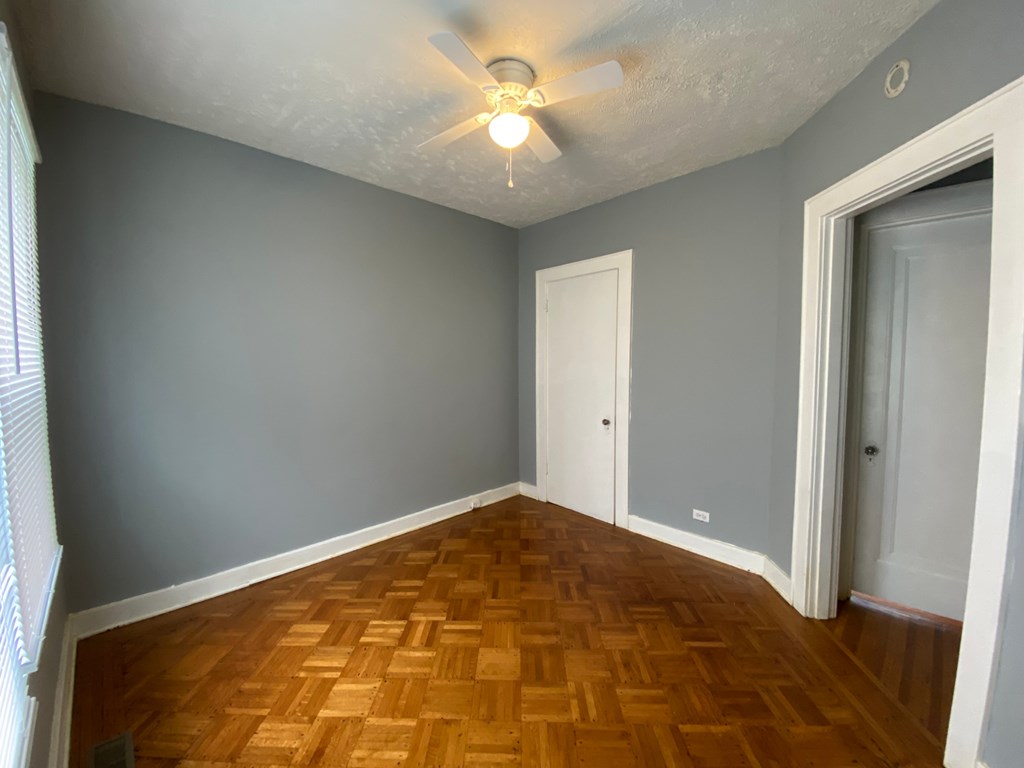A room with wooden flooring and a ceiling fan.