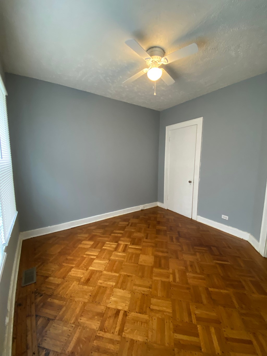 A room with a ceiling fan and wooden flooring.