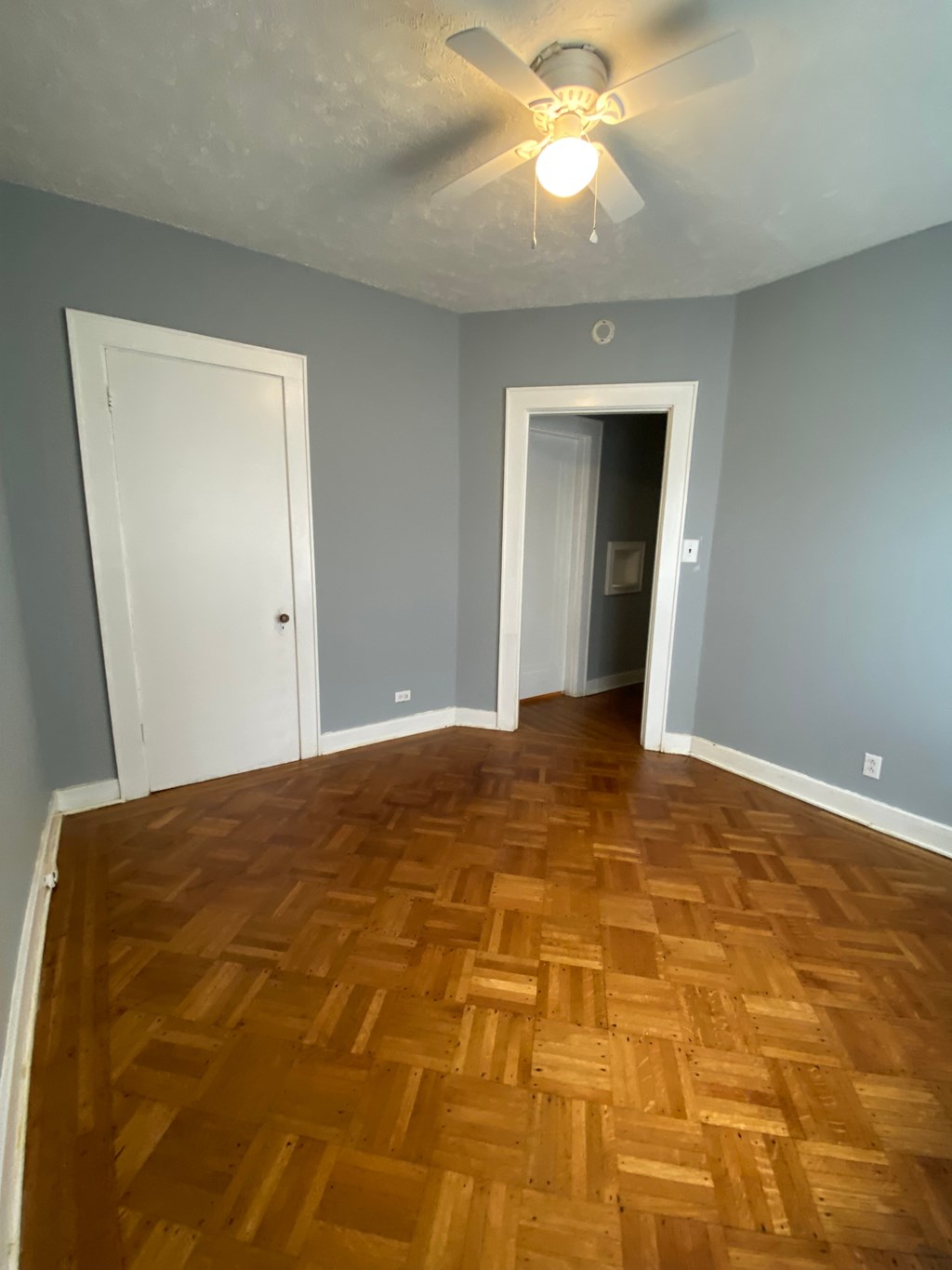 A room with a wooden floor and a ceiling fan.