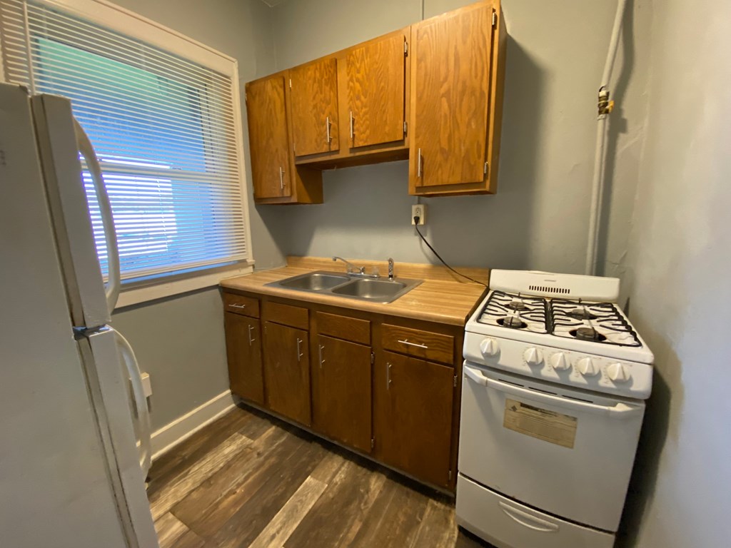 A kitchen with a white stove and wooden cabinets.