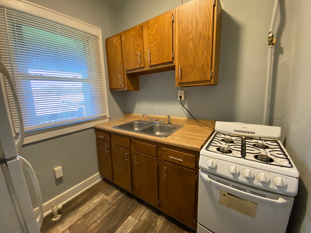 A kitchen with a white stove and wooden cabinets.