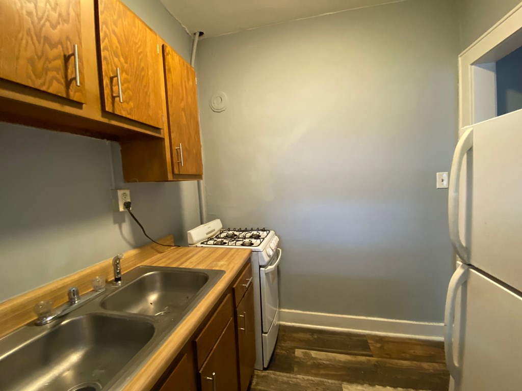 A kitchen with a stove, sink, and refrigerator.