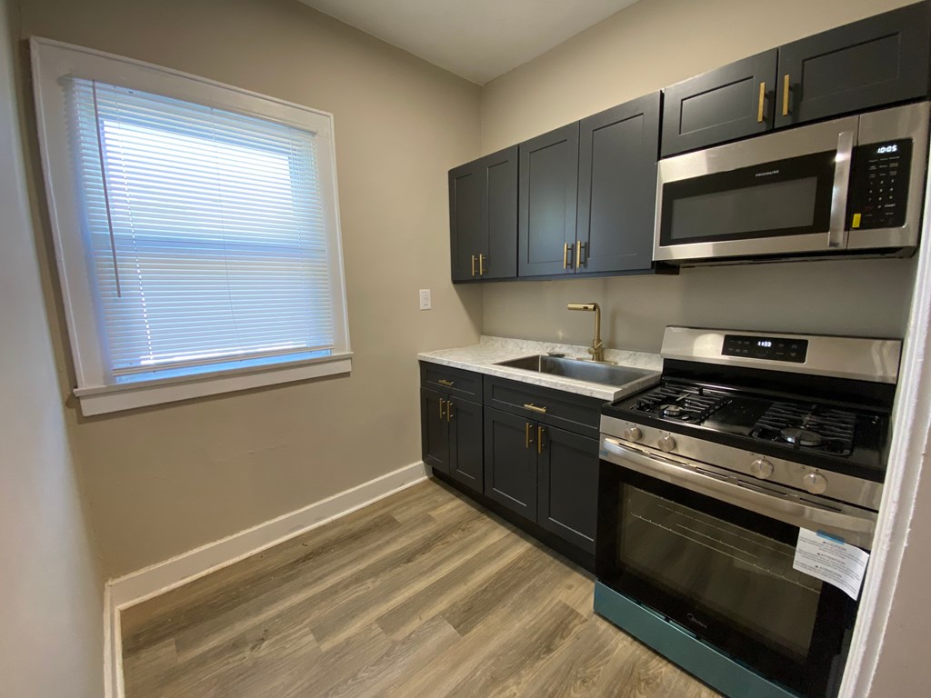 A kitchen with black cabinets and a stainless steel oven.