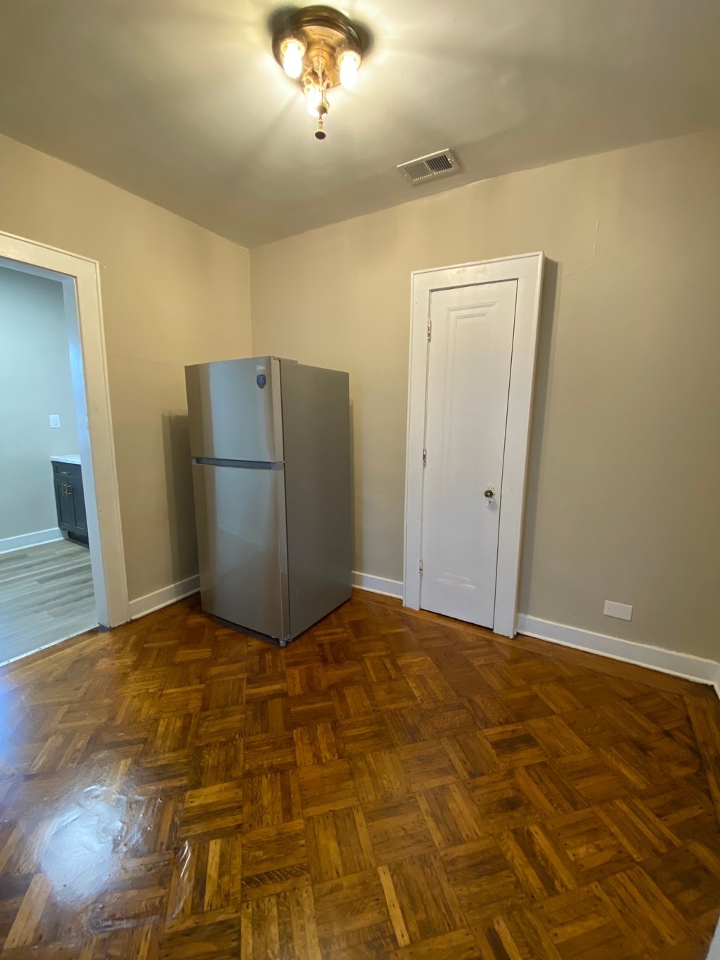 A kitchen with a wooden floor and a fridge.