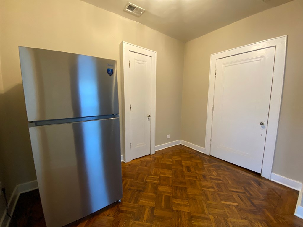 A kitchen with a stainless steel refrigerator and wooden floors.