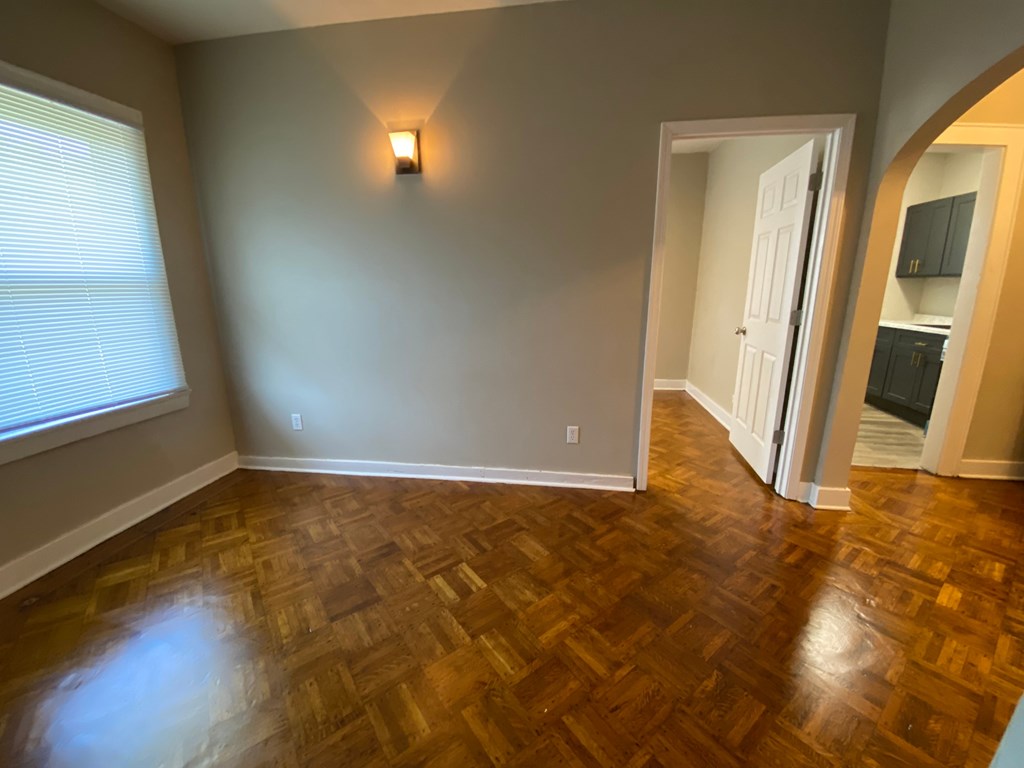 A room with a wooden floor and a light on the wall.