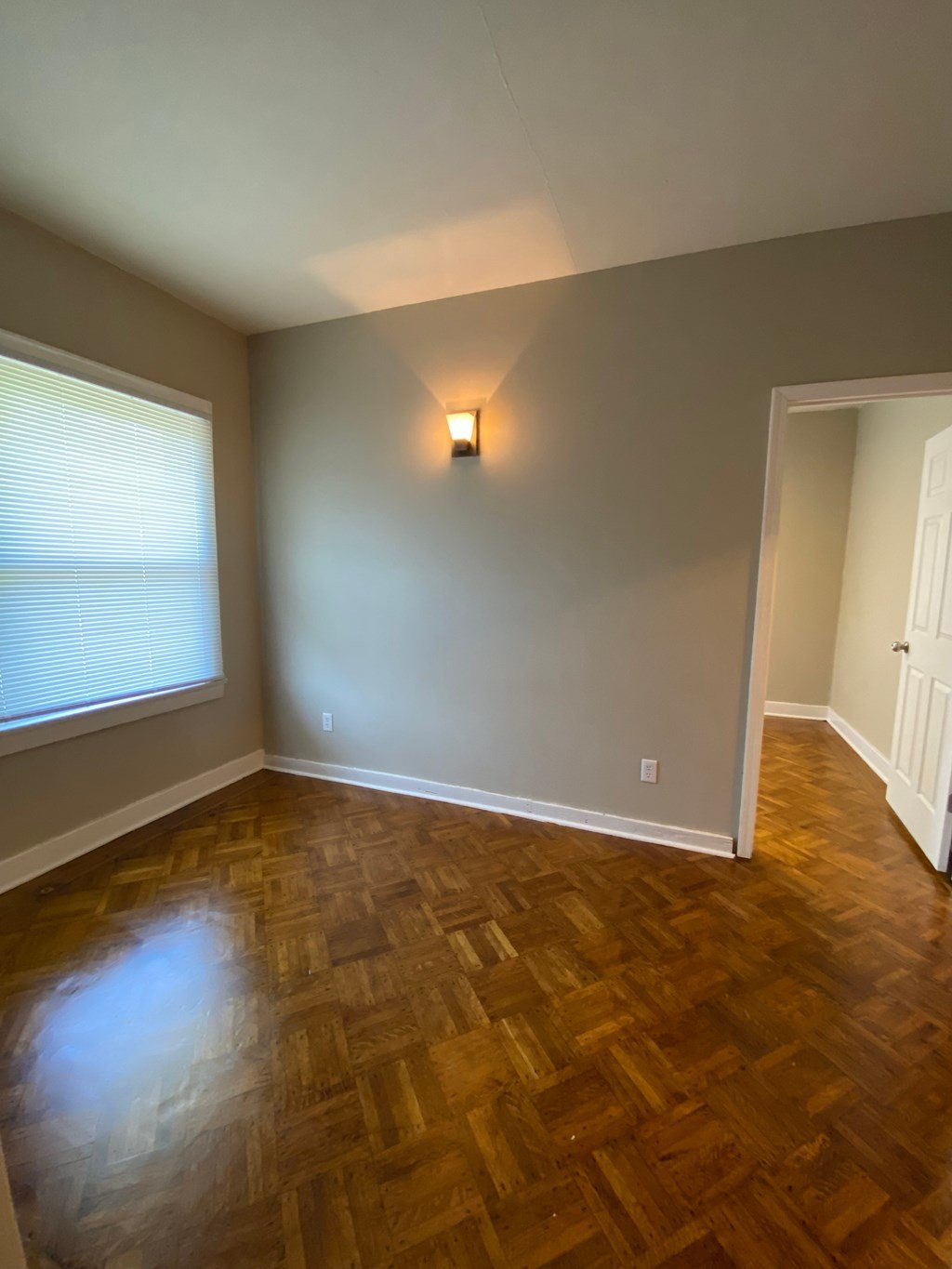 A room with wooden flooring and a light on the wall.