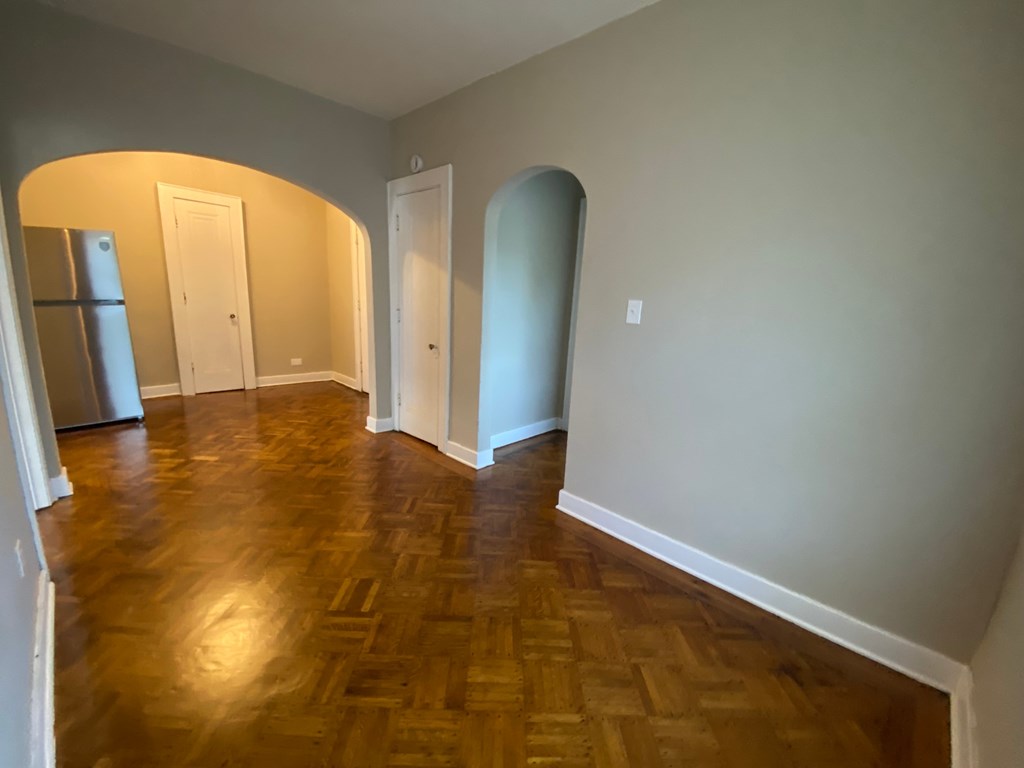 A room with wooden floors and arched doorways.