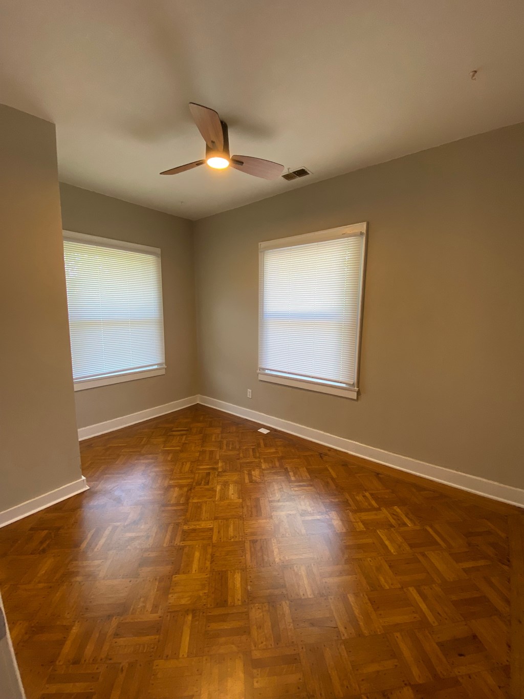 A room with a ceiling fan and wooden flooring.