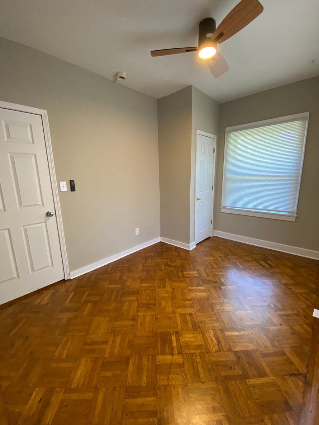 A room with a wooden floor and a ceiling fan.