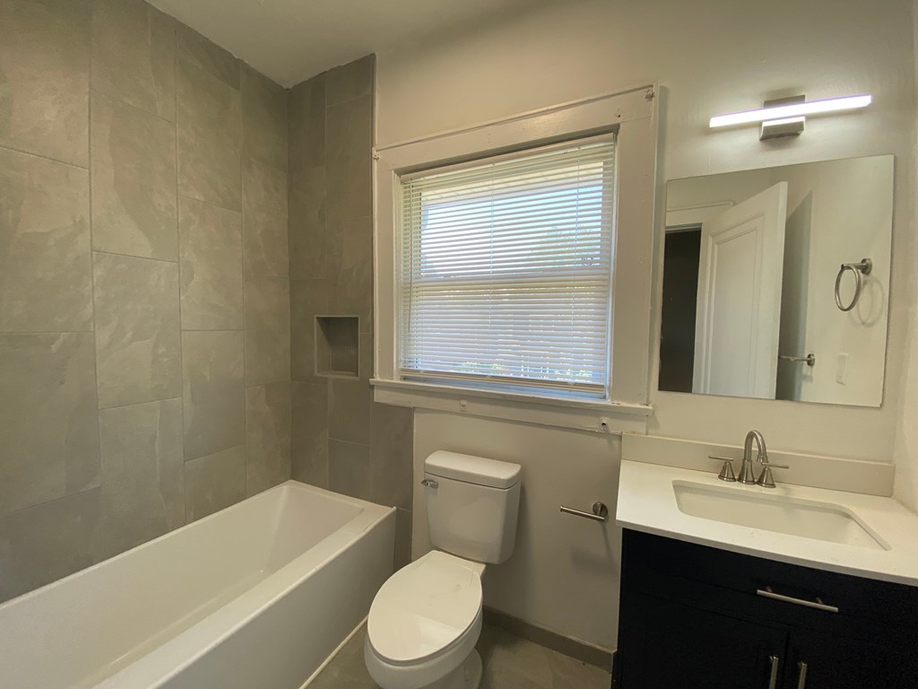 A bathroom with a white toilet and a white bathtub.