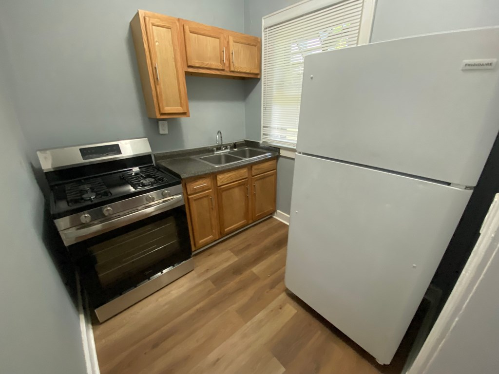 A kitchen with a white refrigerator, stove, and sink.