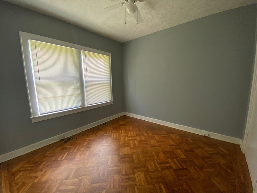 A room with wooden flooring and a window with blinds.